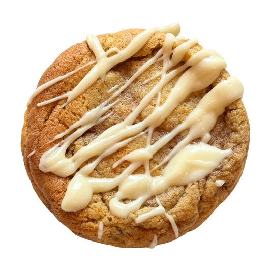 Cinnamon flavoured cookie with white glaze drizzle on a white background